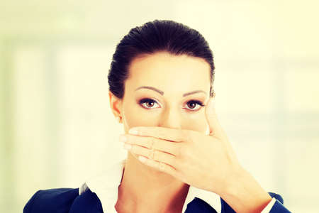 Portrait of young business woman covering with hand her mouth, isolated on white backgroundの写真素材