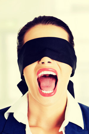 Portrait of a beautiful frighten young blindfold woman screamingの写真素材