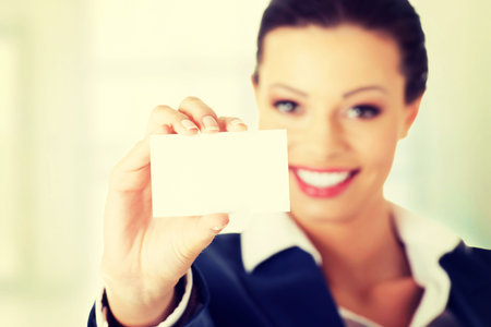 Beautiful smiling businesswoman with businesscard. Isolated on whiteの写真素材