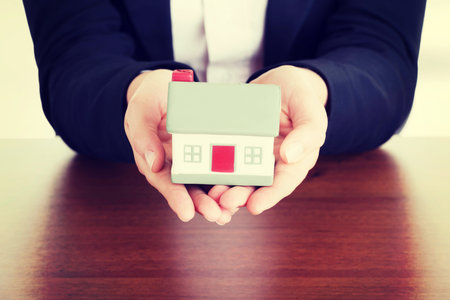 Businesswoman with house model over white - real estate loan conceptの写真素材