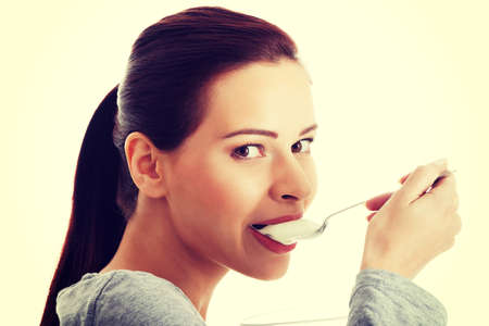 Young casual woman eating a yoghurt. Isolated on white.の写真素材