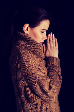 Young woman praying. Over black background.の写真素材