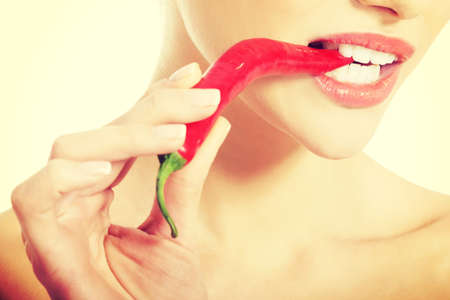 Beautiful caucasian topless woman with chili pepper in mouth. Isolated on white.の写真素材