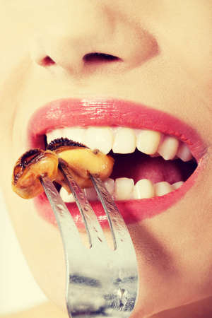 Smiling caucasian woman eating sea fruit with fork. Isolated on white.の写真素材