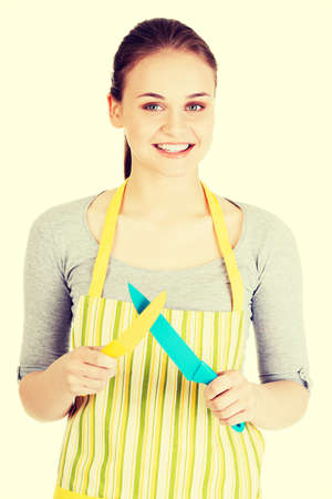 Attractive woman in kitchen apron with knives. Isolated on white.の写真素材