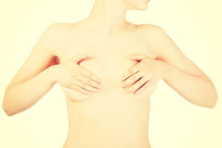 Beautiful woman covering her breasts. Closeup. Isolated on white.の写真素材
