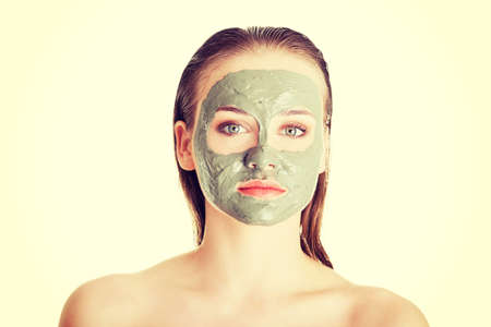Beautiful woman with green clay facial mask, isolated on whiteの写真素材