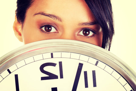 Portrait of shocked woman with clock over white background