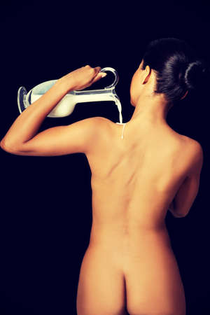 A photo of rear view naked sexy woman splashing milk on her body.の写真素材