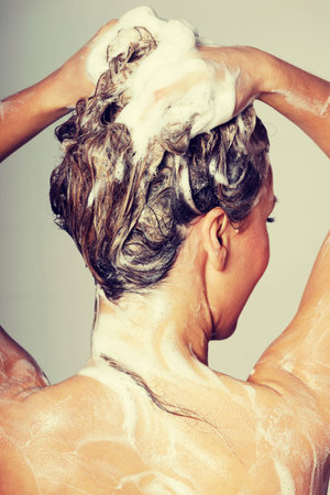Woman taking a shower and shampooing her hairの写真素材