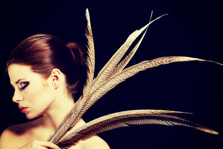 Beautiful woman with brown professional make-up with feathersの写真素材
