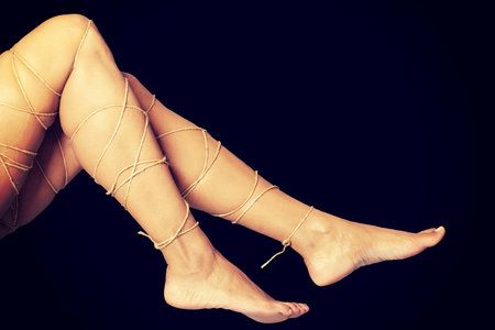 Legs pain concept - legs tied with rope isolated
