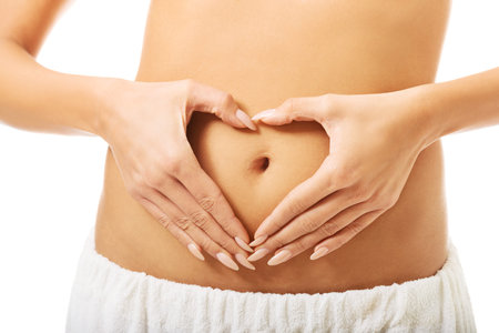 Spa woman making heart shape on belly.
