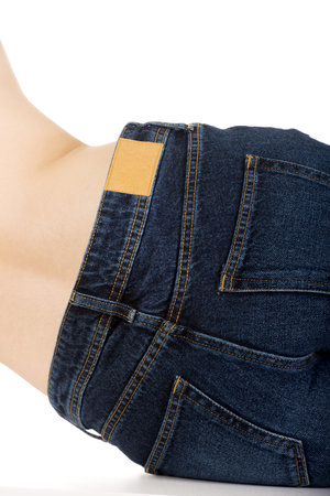 Shirtless young woman lying in jeans shorts.