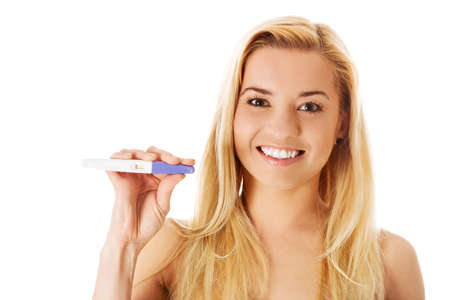 Happy young woman holding positive pregnancy test. Isolated on white.の写真素材