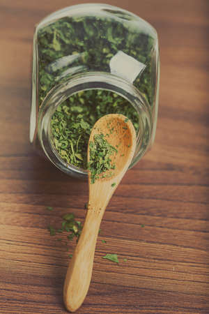 Dry parsley in glass jar with wooden spoon.の写真素材