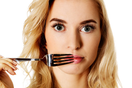 Woman touching her lips with fork.の写真素材