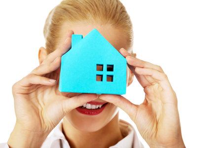 Smile business woman looking through a paper house window.の写真素材