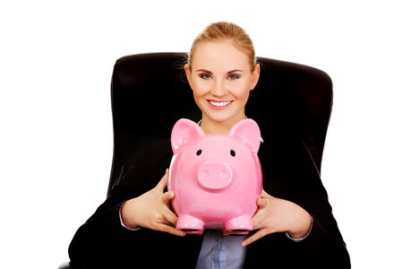 Business woman sitting on armchair and holding piggybank.の写真素材