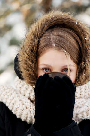 Teenager drinking hot drink in the winter outdoorsの写真素材