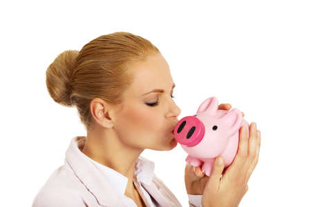 Young business woman kissing a piggybank.の写真素材