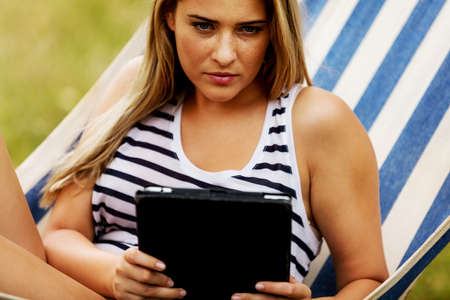 Young woman with tablet on the hammock.の写真素材