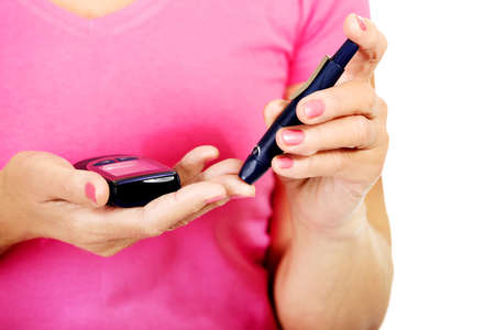 Senior woman with glucometer checking blood sugar level.の写真素材