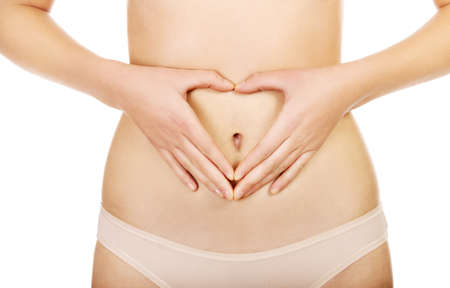 Woman is having heart shape made from hands on her belly.の写真素材