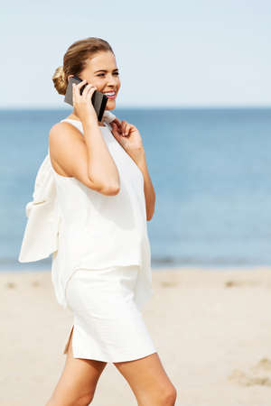 Young elegant beautiful woman talking on the phone on the beach.の写真素材