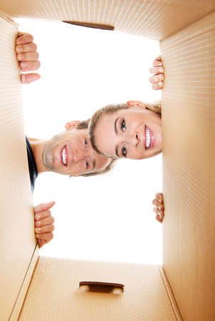 Happy young couple opening a carton box and looking inside.の写真素材