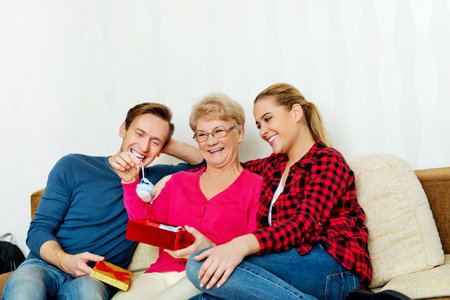 Happy family - couple with old woman who holding gift box and baby shoe.