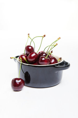 Juicy fresh cherries in black vessel.の写真素材