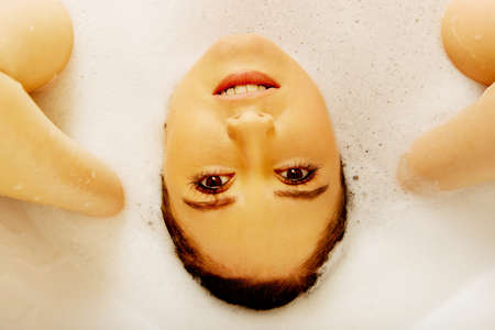 Young woman washing hair in bath.の写真素材