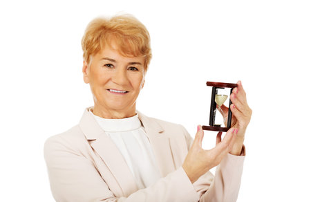 Smile elderly  business woman holding sandglass.