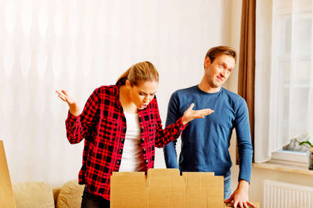 Couple unpaking boxes, stressed woman looking to inside.の写真素材