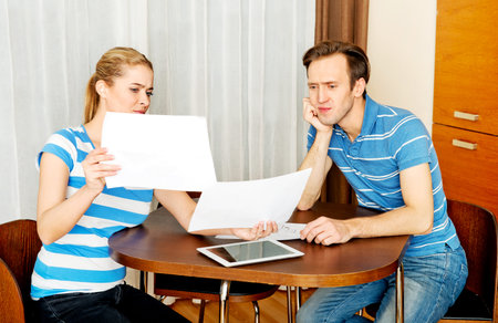 Young couple sitting at the desk and looking for plans of new house.
