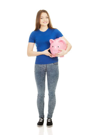Happy teenage woman holding piggybank.の写真素材