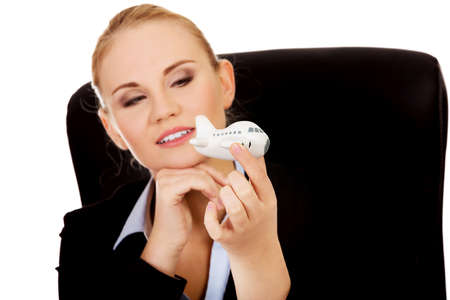 Business woman sitting behind the desk and holding a toy plane.の写真素材