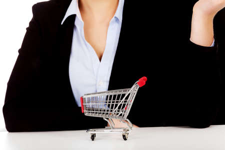 Business woman sitting behind the desk with shopping cart.の写真素材