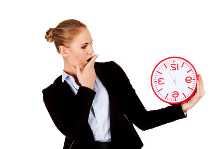 Yawning business woman holding office clock.の写真素材