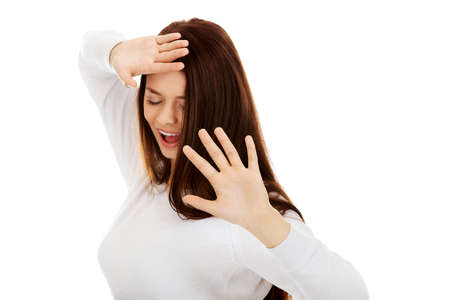 Amused young woman hides behind her hands.の写真素材