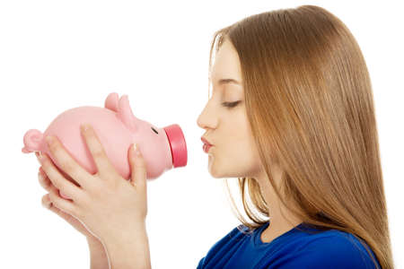 Happy teenage woman kissing piggybank.の写真素材