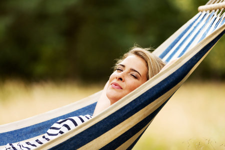 Young blonde woman resting on hammock.の写真素材