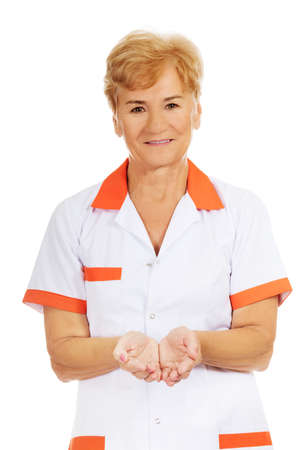 Smile elderly female doctor or nurse presenting something on open palms.の写真素材