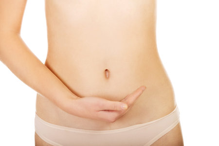 Young woman belly with hand on it.