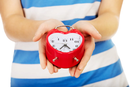 Teenage woman showing alarm clock.