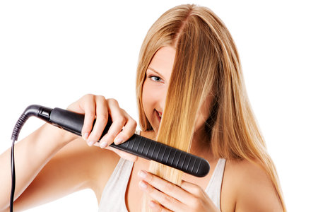 Portrait of beautiful woman using hair straighteners
