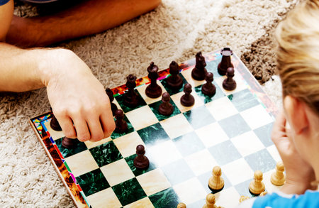 Focused happy couple playing chess on the floor.の写真素材