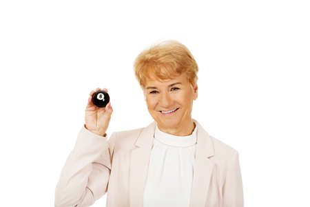 Happy elderly business woman holding eight billard-ball.の写真素材