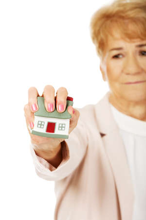 Elderly angry business woman crushed house model.の写真素材